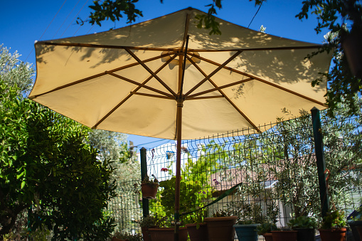 A close-up view from the low, a beautiful opaque bronze umbrella floating freely in the blue sky in the springtime sunlight of the Thai countryside.