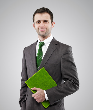 Young businessman holding a green book and smiling.