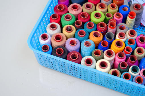 Rolls of colorful cotton threads with reflections on white background, regular composition