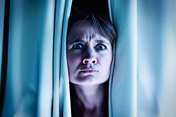 istock Is that an intruder? Nervous blonde frowns through curtains 170034678