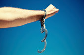 Single open handcuff on male arm symbolizing freedom