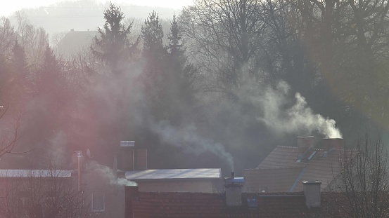 Smoke Fumes Raising from Chimneys in Residential Houses in Winter Backlight