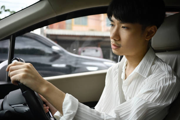 istock A shot from inside a car with a sleepy-looking Asian man driving a car. falling asleep while driving 1700358158