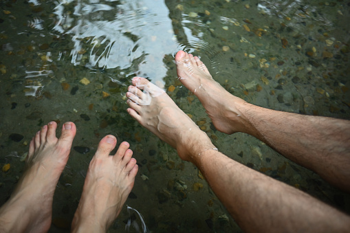 Close-up image of Two male's feet soaking in the hot springs.