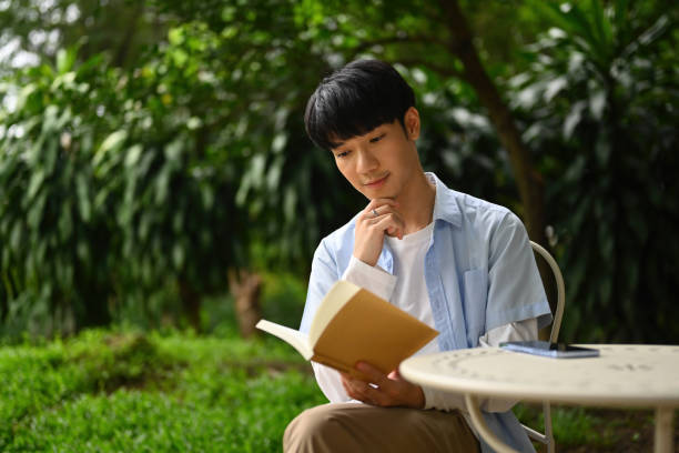 istock A young Asian man reading a book while sitting in the garden 1700361044