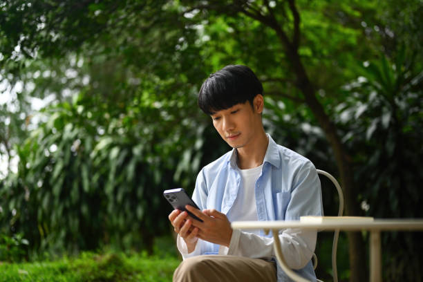 istock A young Asian man using with a smartphone while sitting in the garden 1700361046