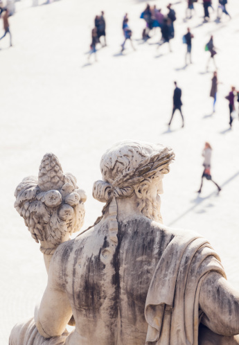 Statue on Piazza del Popolo in Rome looking on the walking people.