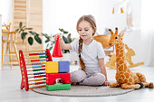 a little girl among the toys in the children's bright room at home or in kindergarten is a pyramid of cubes, a smiling child, the lifestyle of a preschooler child