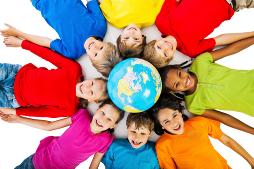 Group of children lying on the floor in circle with the globe above their heads. 