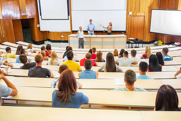 Students at the lecture. Professors and assistants explaining a lecture to a group of college students.    lecture hall photos stock pictures, royalty-free photos & images