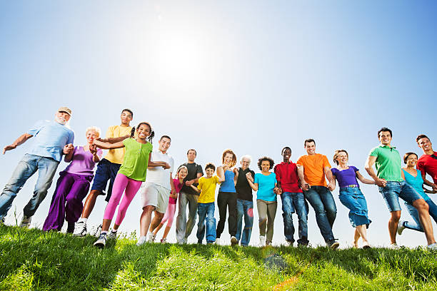 Young female athletes showing teamwork and friendship, stacking hands in a huddle against a blue sky