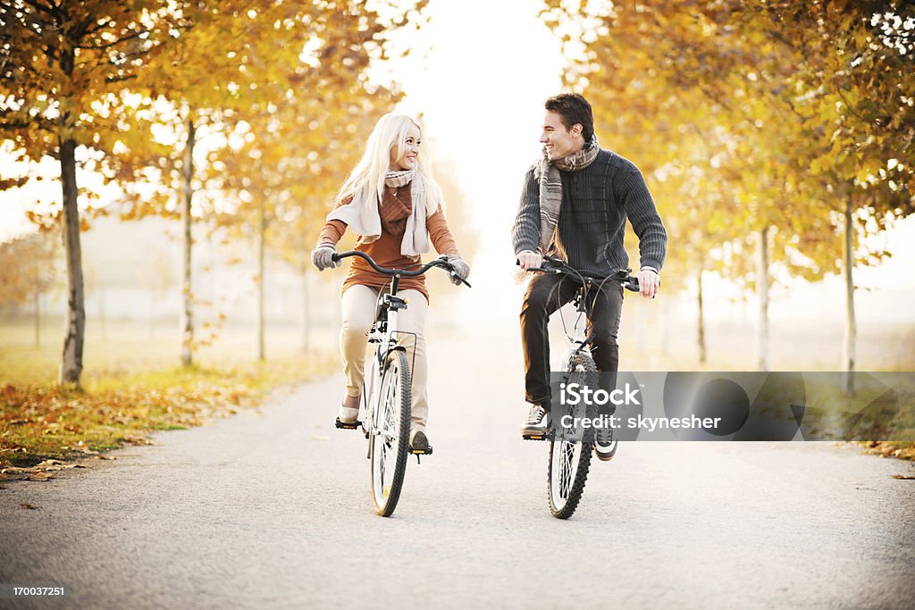 Bella coppia cavalca biciclette in giornata autunnale. - Foto stock royalty-free di Autunno