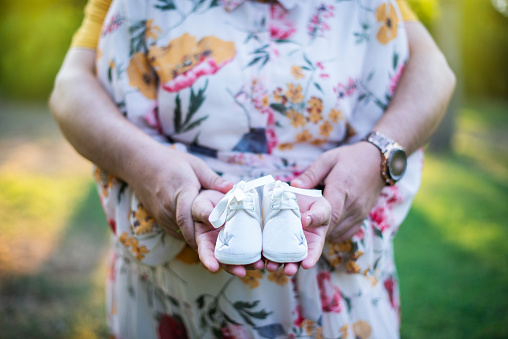 a husband and wife holding baby shoes. Expectant parents expecting a baby