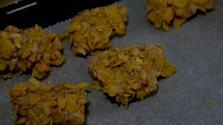 hand arranging chicken nuggets with corn flakes on a tray