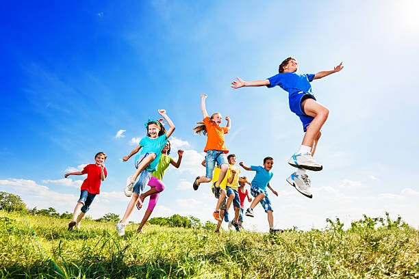 alegre crianças pulando em campo contra o céu. - dia das crianças - fotografias e filmes do acervo