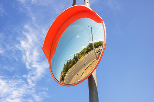 Spherical Road Mirror on blue sky background close up