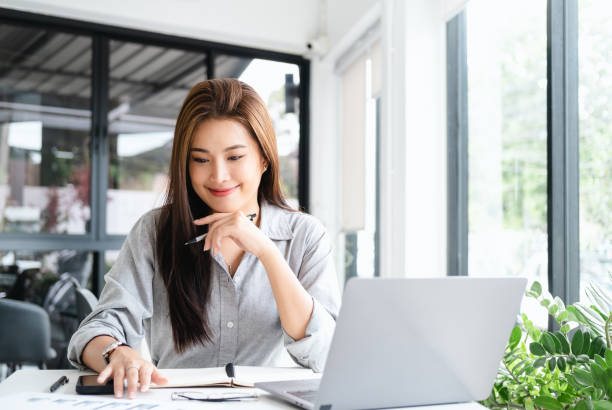istock smiling beautiful business asian woman working in office use computer with copy space. Business owner people sme freelance online marketing e-commerce telemarketing, work from home concept 1700415539