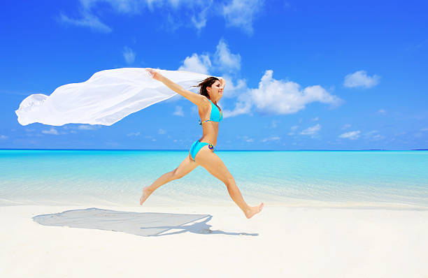 istock Happy woman running on a beach with long sarong. 170041744