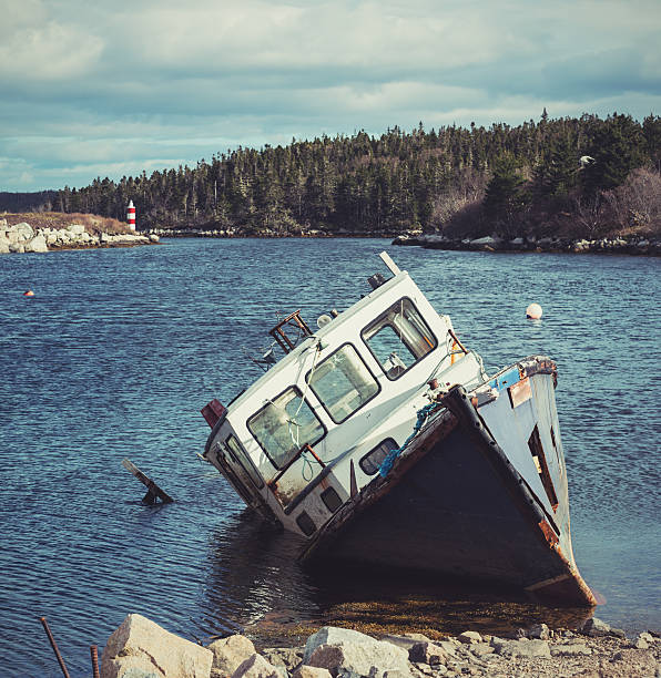 An abandoned fishing boat sits on the shores of a small cove.