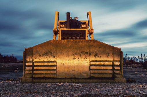 A large bulldozer on a construction site at dusk.  Long exposure.