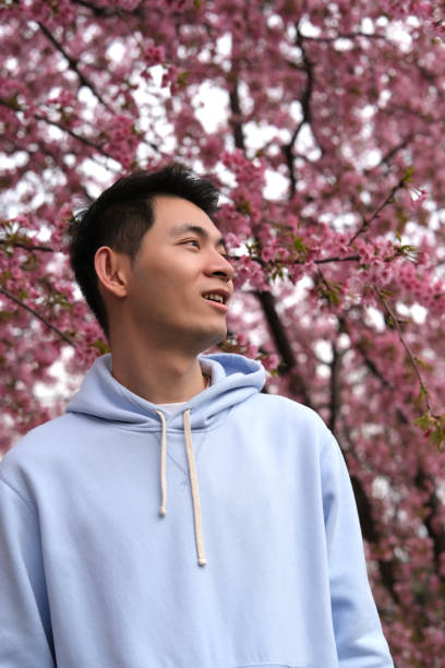 istock cute Asian young man side view with blur pink sakura flowers 1700426182