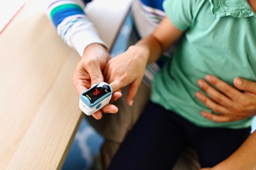 Close-up of a little girl using a pulse oximeter at home