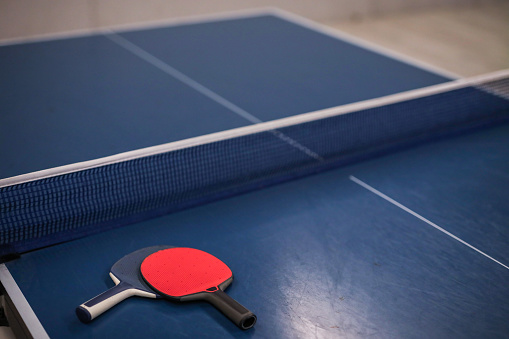 Red And Dark Blue Rackets Stand On The Table Tennis Table