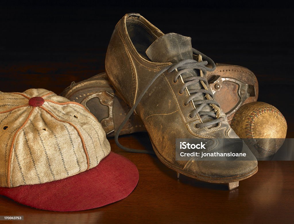 Antique baseball items on wood A pair of old weathered cleats, an antique baseball and a  baseball cap warmly lit on a wooden background. Retro Style Stock Photo