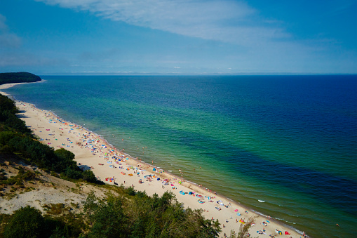 Aerial view of sea landscape with crowded sand beach in Wladyslawowo. Baltic sea coastline with swimming people in Poland. Resort town in summer season