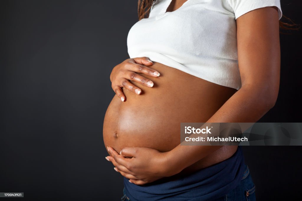 Embarazada African Woman Holding Her Belly - Foto de stock de Embarazada libre de derechos