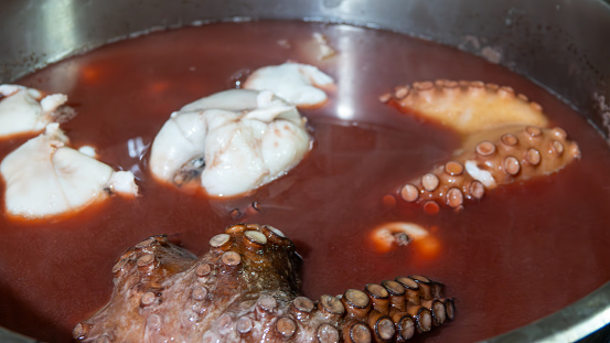 Boiled octopus marinated with various herbs and bay leaves in a large pot