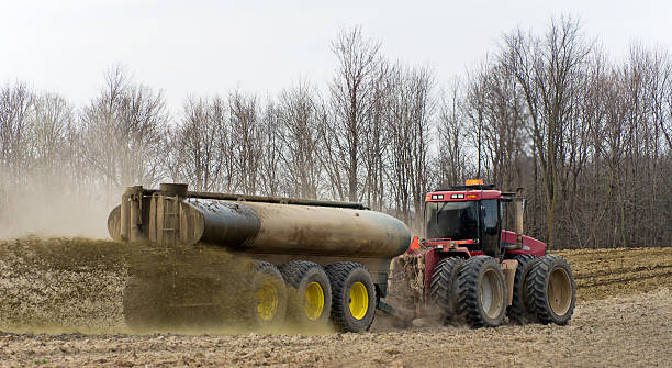 Farmer Spreading Liquid Manure A farmer with a large tractor spreading liquid manure on a ploughed field on an overcast spring day. animal dung stock pictures, royalty-free photos & images