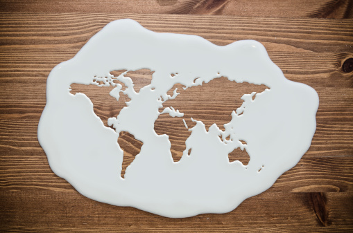 milk concept - liquid world map on a wooden table