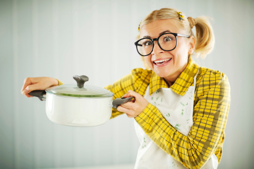 Housewife with big black glasses holding a saucepan.