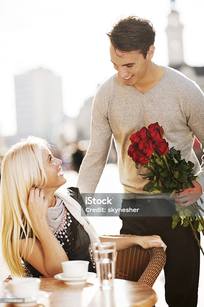 Teenage love couple meeting at cafe for Valetine's Day Man giving his girlfriend a bouquet of roses for Valentine's day.    Outdoors Stock Photo