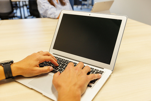 Shot of a young man's hands typing on a laptop.