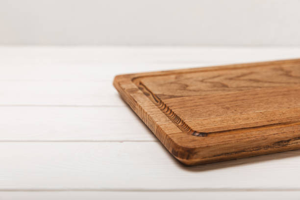 istock Wooden cutting board on a textured kitchen table. Wooden kitchen board and kitchen towel. Design.MOCKUP. Kitchenware. Place for text. Copy space. Recipe. Cooking concept. 1700487428