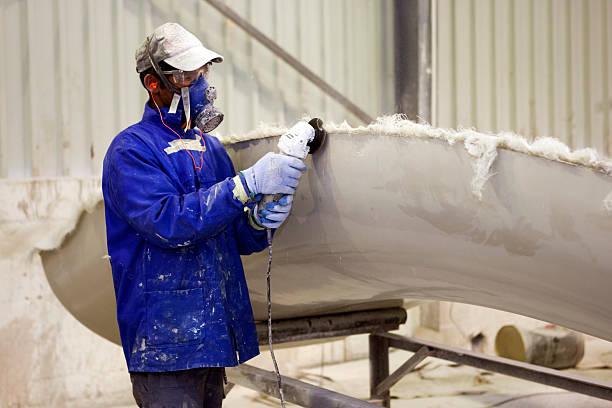 Man with protective gear grinding glass fiber surface Male with protective wear grinding a fibre glass unit. Note: lots of dust in the air due to the grinding fibreglass stock pictures, royalty-free photos & images