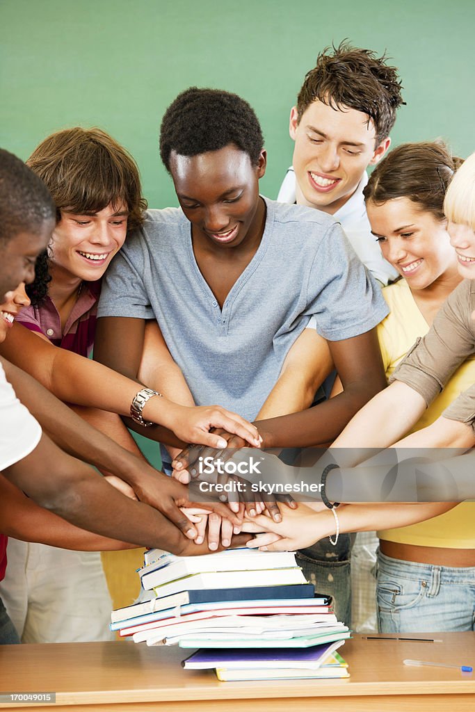 Gruppo di sorridente gli studenti con le mani pilled sui libri. - Foto stock royalty-free di Studente di scuola secondaria - Studente