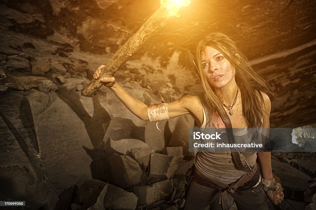 Heroína feminino olhando em uma caverna com tocha - Foto de stock de Tocha de Fogo royalty-free