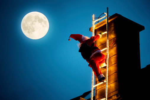 Santa Claus puppet is climbing up an illuminated chimney. Full moon in the sky. Christmas decoration. Vignette. Low angle view. XXXL (Canon Eos 1Ds Mark III)