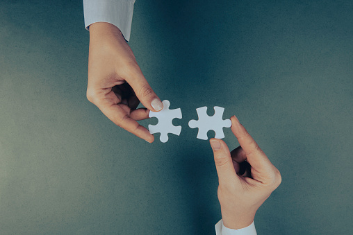 Business people are merging two puzzle pieces.