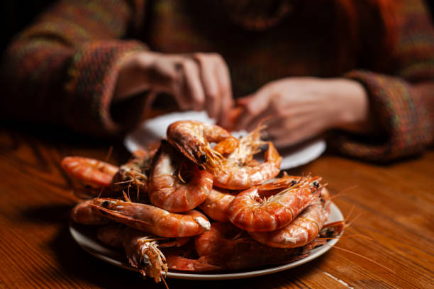 istock Large cooked king prawns on the table. An unrecognizable man is eating shrimp at the table. 1700504978