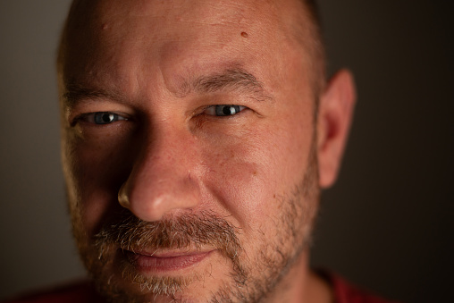 A close-up portrait capturing the friendly and welcoming nature of a 40-year-old unshaved man with a commonplace appearance