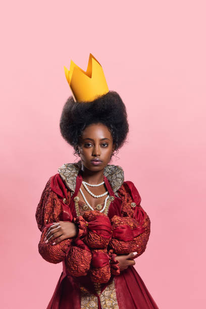 portret młodej, pięknej afrykańskiej kobiety, średniowiecznej księżniczki w zabytkowej sukni z papierową koroną na różowym tle studyjnym - women crown princess 20s zdjęcia i obrazy z banku zdjęć