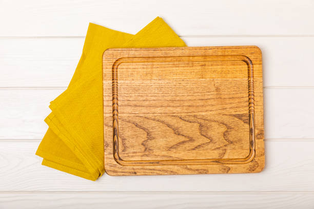 istock Wooden cutting board on a textured kitchen table. Wooden kitchen board and kitchen towel. Design.MOCKUP. Kitchenware. Place for text. Copy space. Recipe. Cooking concept. 1700512009