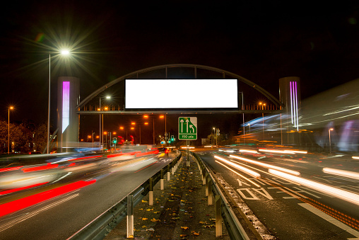 A digital out of home media billboard at night with traffic light streaks
