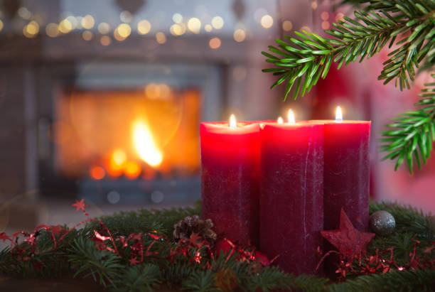 Four burning red Advent candles in a warm interior with fireplace. stock photo