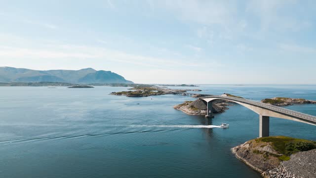 Aerial view of a boat sailing under Storseisundet bridge on Atlantic Road (Atlanterhavsveien) also known as ”The Road in the Ocean” in Norway. National Tourist Route