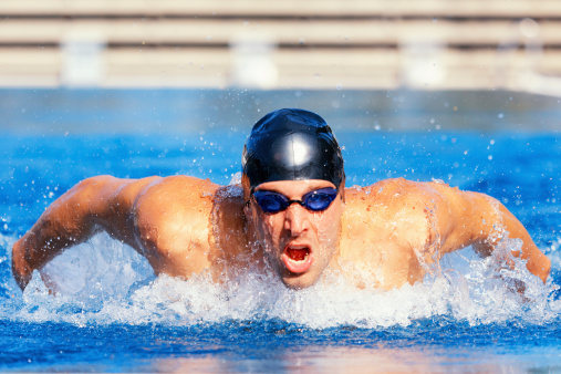 front view butterfly swimmer with cap and goggles breathing